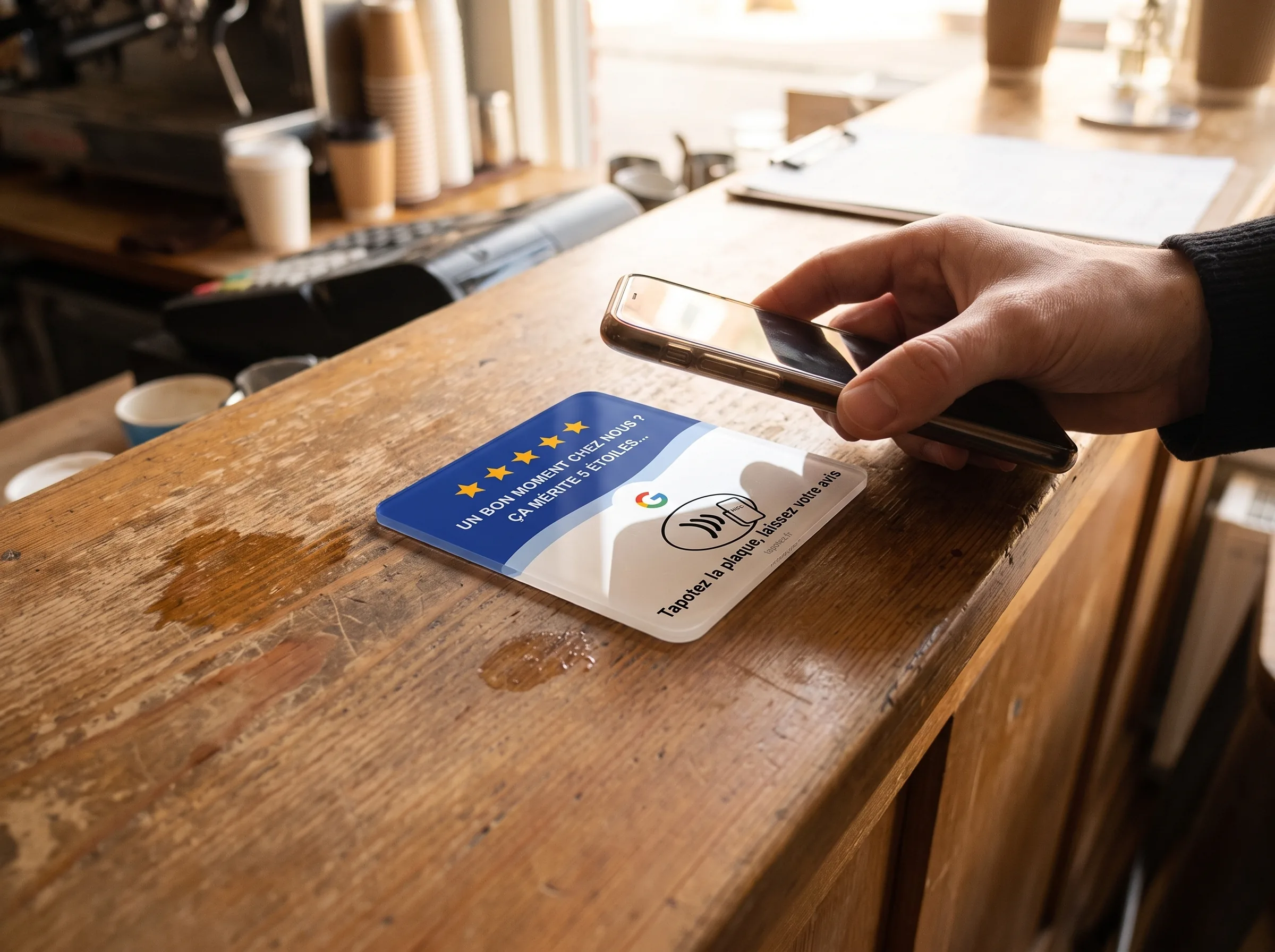 Un client tapote son téléphone sur la plaque Tapotez posée sur le comptoir d'un café